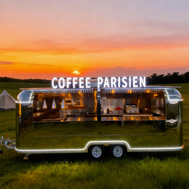 Food Trailer Airstream with bright 'COFFEE PARISIEN' signage at sunset, showcasing sleek stainless steel design.