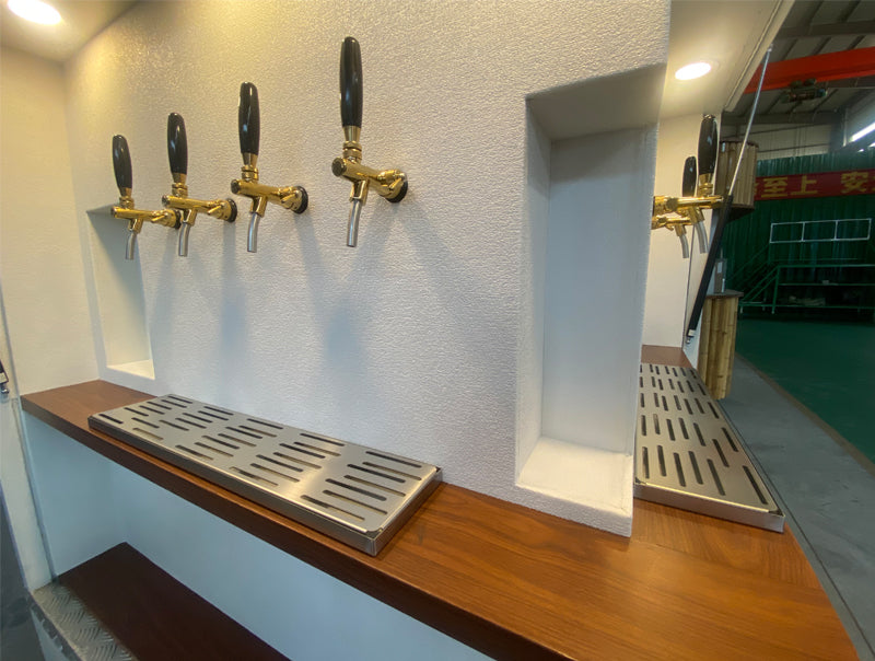 Food truck interior featuring a polished wooden counter with multiple beer taps and stainless steel drain trays.