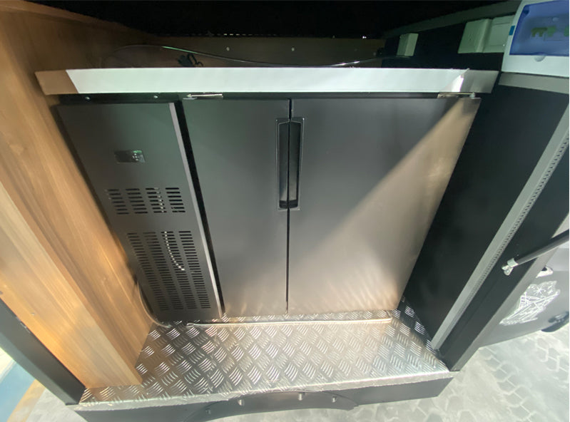 Interior view of a Wedding Bartender mobile beer bar with sleek black fridge and stylish design features.