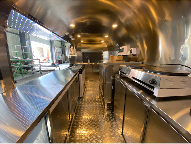 Interior view of a Food Trailer Airstream showcasing the full stainless steel kitchen and modern appliances.