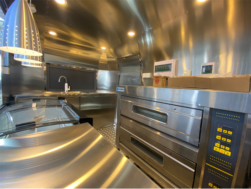 Interior view of a professional Food Trailer Airstream mobile kitchen featuring stainless steel appliances.